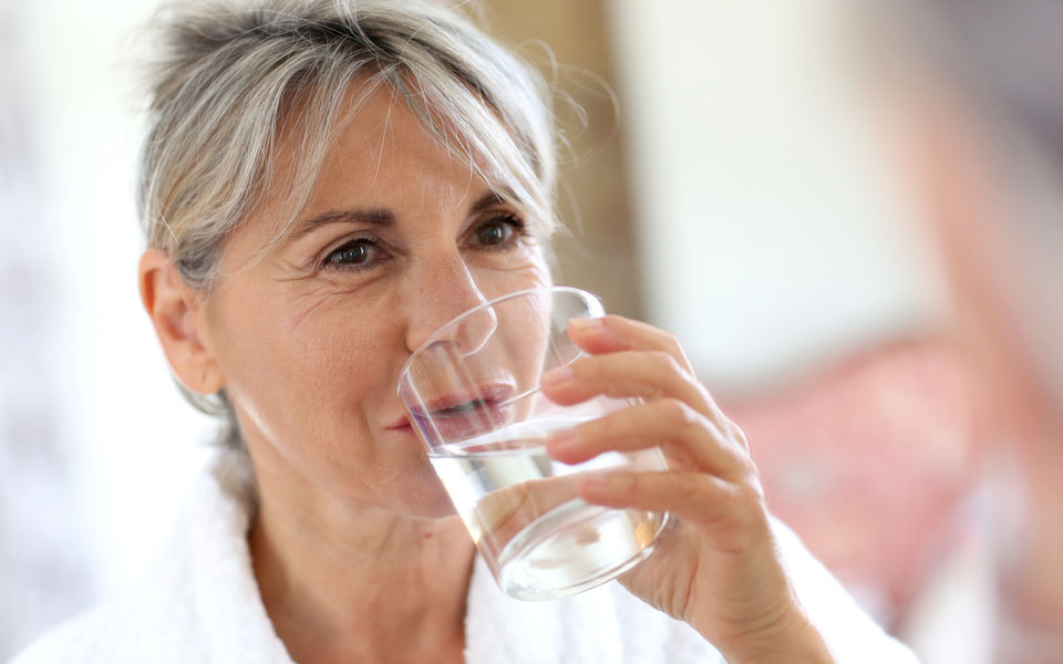 Frau mittleren Alters trinkt ein Glas Wasser